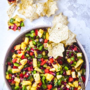 pomegranate pineapple salsa hero shot in bowl with chips and spoon