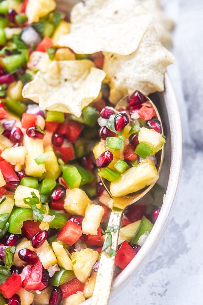 pomegranate pineapple salsa presented on a gold spoon