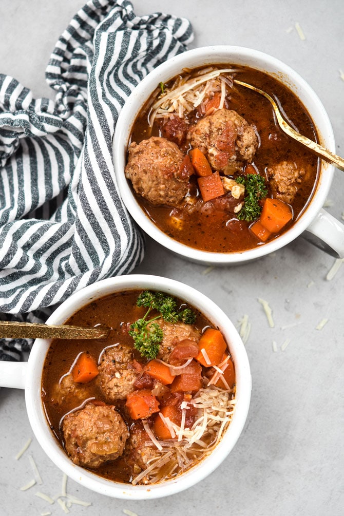 meatball soup in two bowls with gold spoons