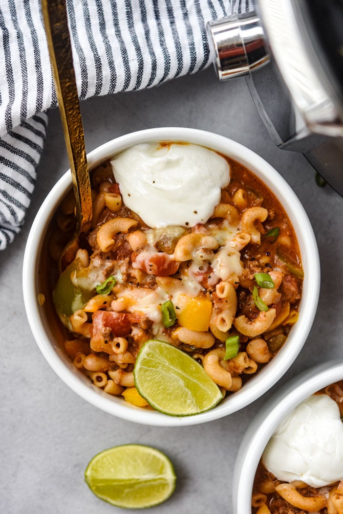 chili mac in bowl with sour cream and gold fork