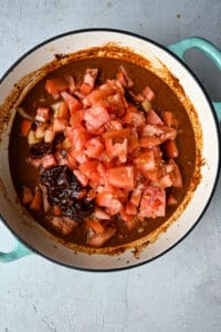 adding tomatoes and chipotles to enchilada