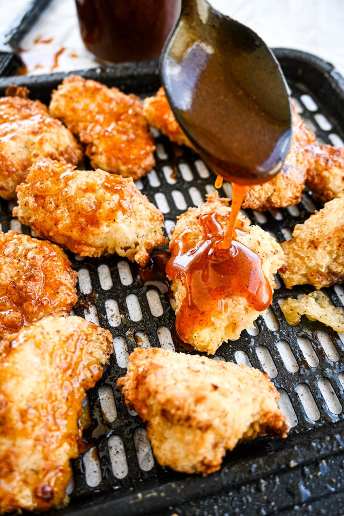 hot honey sauce being drizzled on cooked crispy chicken tenders