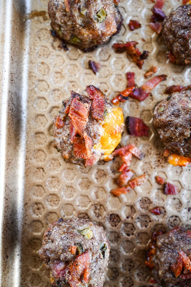 cooked cheeseburger meatball on a sheet pan with bacon bits