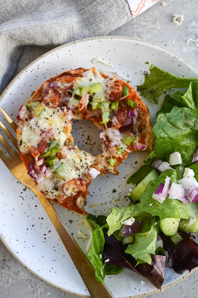 cooked pizza on plate with salad with bite taken